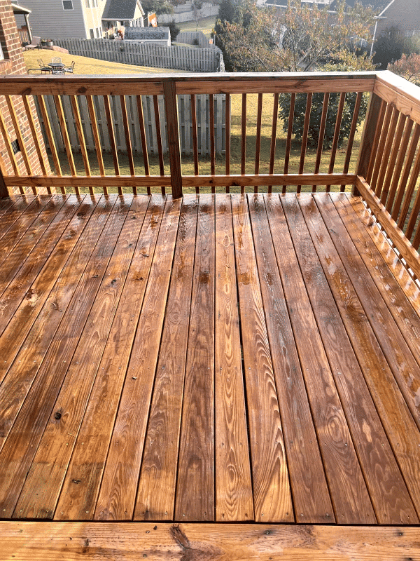 Freshly stained wooden deck with a clean finish, showcasing natural wood grain and a sunny day.