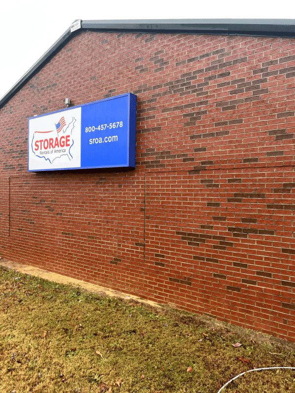 Storage facility exterior with sign displaying contact information and website.