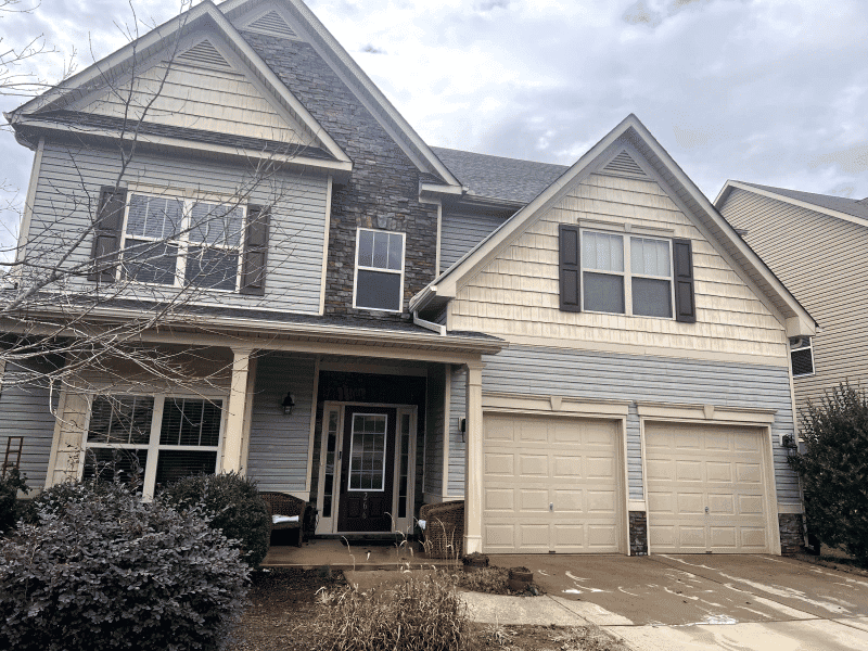 Two-story residential home with mixed siding, two garage doors, and landscaped front yard.
