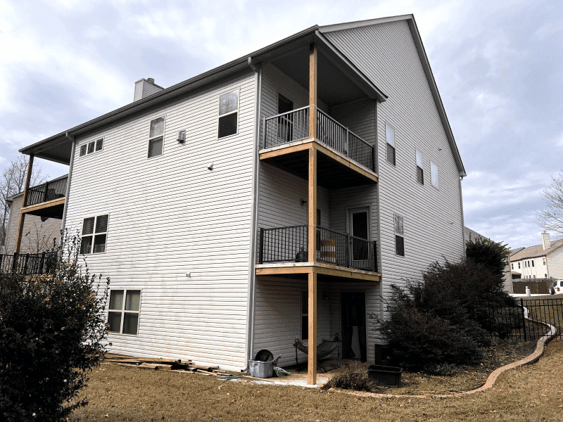 Two-story residential home with balconies, vinyl siding, and outdoor space.