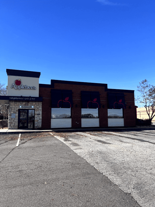 Applebee's restaurant exterior featuring logo and closed roller shutters on a clear day.