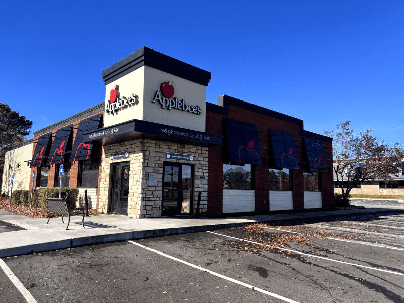 Applebee's restaurant exterior with signage, outdoor seating, and parking lot.