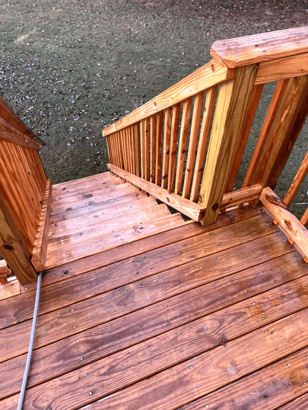 Wooden staircase with railings and polished wooden steps in a grassy area.