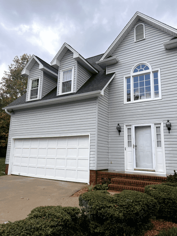 Gray two-story house with multiple gables, decorative windows, and a double garage door.