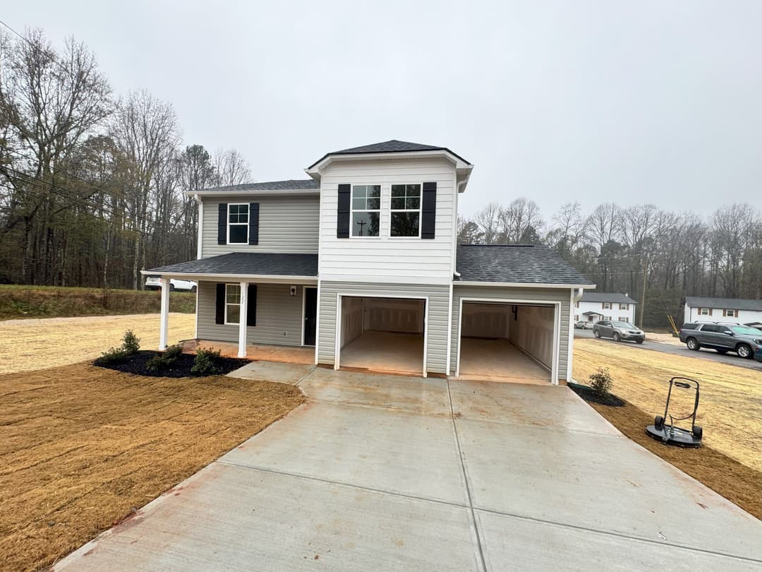 New two-story home with garage, modern design, and landscaped yard on a cloudy day.