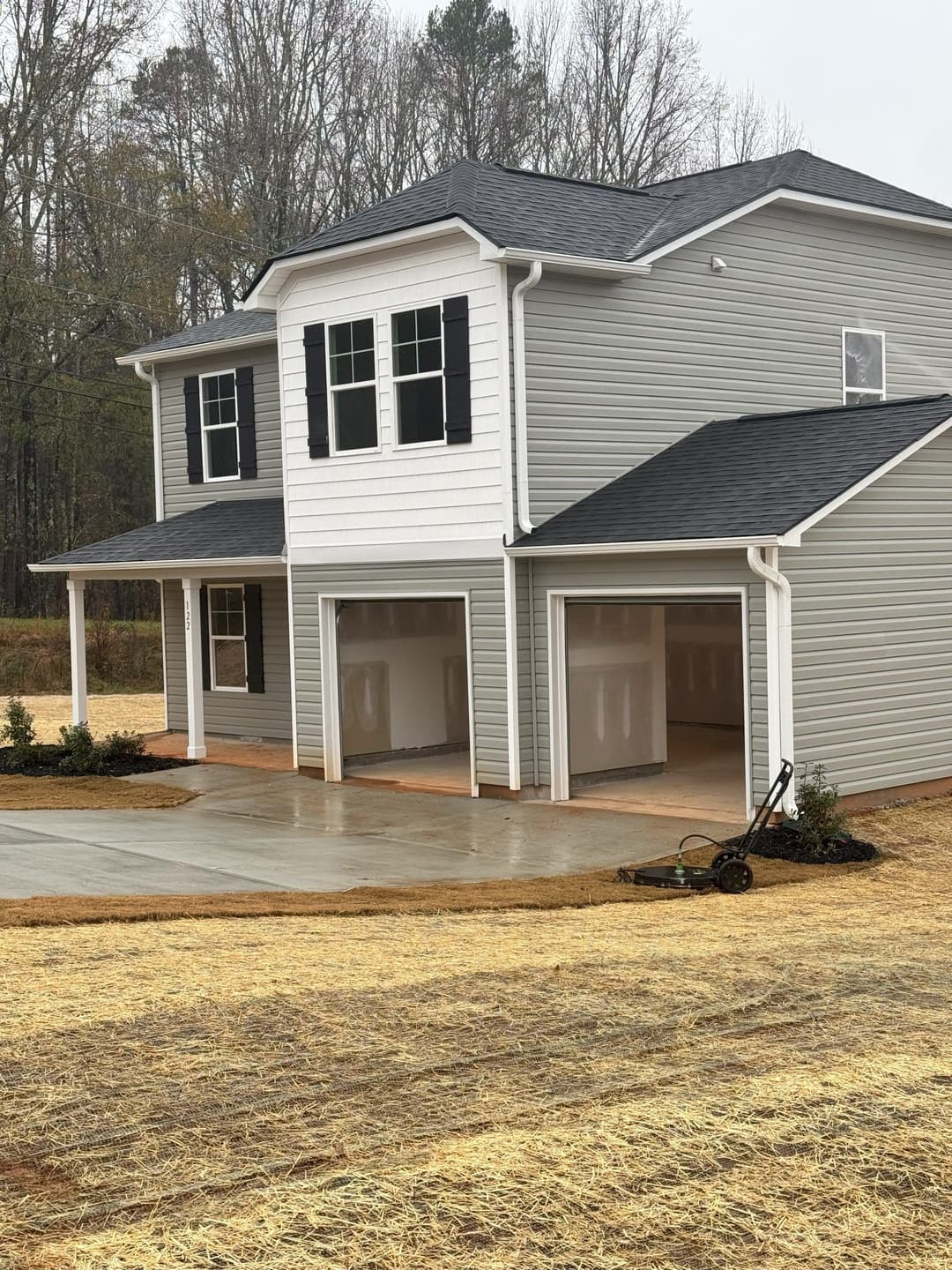 Newly constructed gray house with double garage and manicured landscaping.