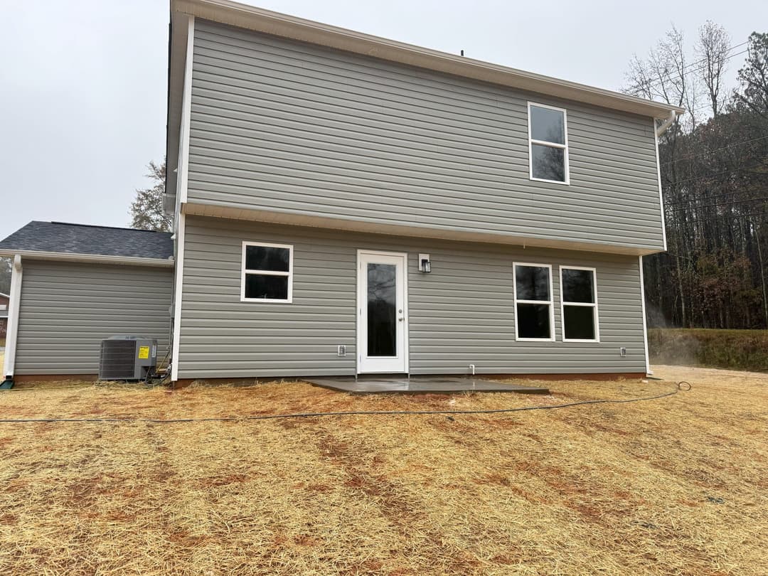 New modern two-story home exterior with gray siding and large windows on a grassy lot.